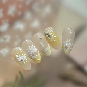 Elegant almond press-on nails with embossed white butterflies and pearls on gradient yellow