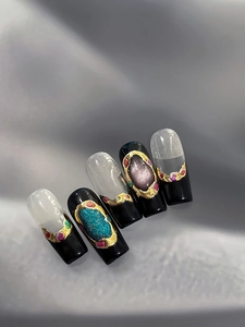 Détail de nail art baroque noir et or avec strass sur un tissu en soie gris