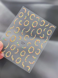 Détail des stickers ongles dorés YT7126 avec pierres colorées sur fond sombre