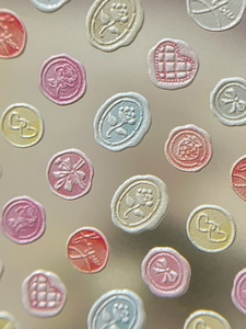 Macro detail of 3D embossed wax seal nail stickers with floral and heart patterns
