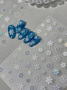 Macro view of metallic silver and laser snowflake nail art stickers on blue nails