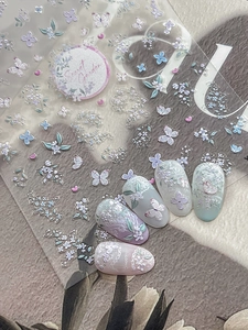 Macro shot of 5D embossed nail stickers featuring purple flowers and white butterflies