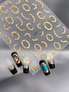 Détail de stickers 3D pour ongles avec relief doré et gemmes colorées sur faux ongles