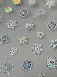 Macro shot of laser silver snowflake nail stickers with blue metal accents and micro-carving