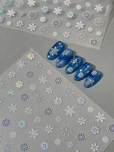 Detailed view of silver laser snowflake nail art stickers on blue gradient manicure
