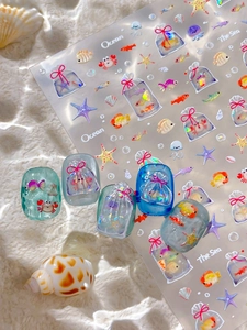 Détail macro de stickers 3D océan avec poissons et coquillages sur capsules d'ongles