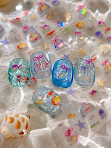 Vue macro détaillée de faux ongles 3D thème océan avec breloques de poissons bleus