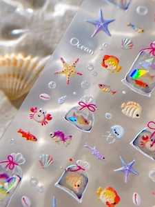 Détail macro de stickers ongles thème marin avec motifs coquillages et poissons