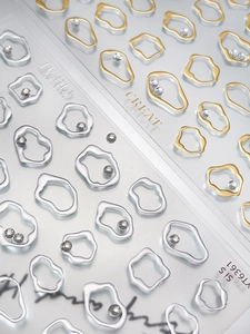 Macro detail of gold and silver irregular metallic nail art stickers with tiny rhinestones