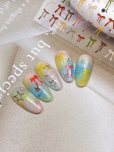 Détail macro de stickers 3D en relief nœuds papillon sur des ongles dégradés décorés