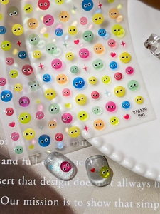 Close-up of cute colorful cartoon face embossed nail stickers on silver glitter nails