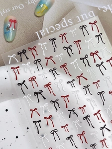 Vue macro de stickers pour ongles nœuds fins en rouge, noir et blanc avec effet relief