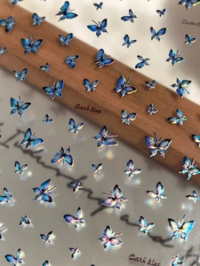 Detail of dark blue holographic laser butterfly nail stickers with iridescent finish
