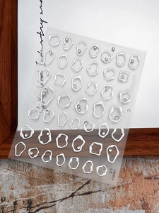Detail view of 3D liquid geometric nail art stickers with silver beads on a white board