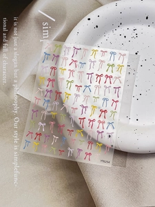 Détail d'autocollants pour ongles avec nœuds colorés sur une assiette décorative