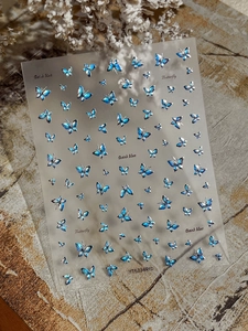 Detail of laser silver and dark blue butterfly nail art stickers on a textured background