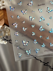 Macro view of iridescent dark blue holographic butterfly nail art decals with detailed texture