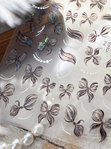 Close-up of holographic 3D bow-knot nail stickers with pearlescent line detailing