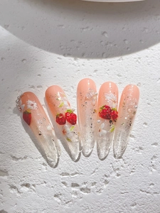 Vue détaillée d'ongles amande longs avec motifs fraise 3D et fleurs en relief