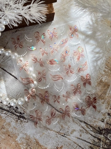 Macro shot of 5D embossed nail stickers featuring rose gold bows and butterflies