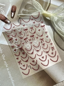 Detail of French lace nail stickers with red heart and bow patterns on nails