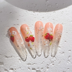 Faux ongles dégradés roses avec motifs fraises, fleurs blanches et perles