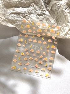 Close-up of holographic nail stickers with pink clouds, yellow moons, and starry sky patterns