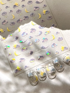 Detail showing dreamy sky nail stickers with laser purple clouds and yellow moon stars