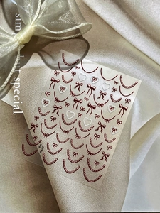 Detail of burgundy lace and bow nail art stickers on elegant velvet fabric background
