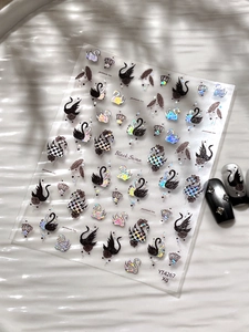 Macro shot of Black Swan nail stickers featuring laser glitter crown and feather patterns