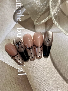 Detail of long coffin nails with black bow accents, lace textures and cat eye finish