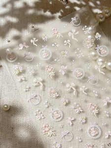 Detail of 3D embossed nail stickers featuring pink flowers, bows and bears on mesh texture
