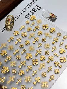Vue macro de breloques à ongles croix et fleur de lys avec strass rouges