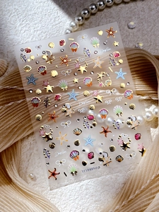 Detailed close-up of gold-stamped ocean theme nail stickers with shells and pearls