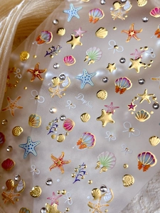 Macro detail of 3D embossed sea shell nail stickers with gold metallic textures