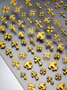 Gros plan d'autocollants pour ongles dorés en relief avec motifs de fleur de lys et croix