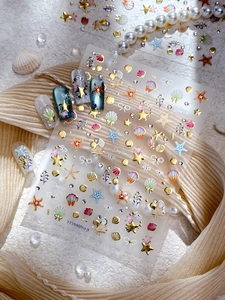 Detail of embossed gold sea shell and starfish nail art stickers with pearl accents