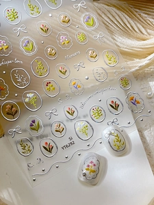 Macro detail of silver embossed floral nail stickers featuring tulips and lavender