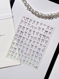 Macro detail of holographic 3D bow nail stickers with laser rainbow glitter effects