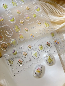 Close-up of 5D embossed silver floral nail stickers with tulip and daisy patterns