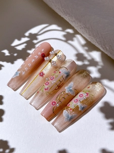 Macro detail of coffin press-on nails with golden butterflies, pearls, and floral art