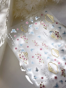 Macro shot of gold foil butterfly and floral nail art stickers with delicate embroidery patterns