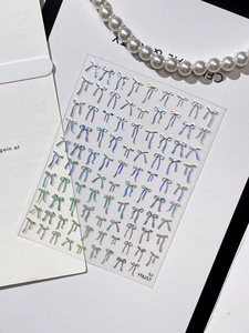 Macro shot of silver laser holographic bow nail stickers with pearl necklace decor
