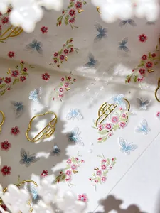Close-up of gold-stamped butterfly and floral embroidery style nail art stickers