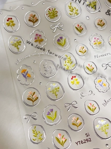Detailed macro view of 3D embossed silver flower nail art stickers with daisy and tulip motifs