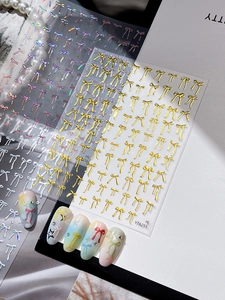Detailed view of 3D bow nail art stickers in gold and iridescent finishes on nails