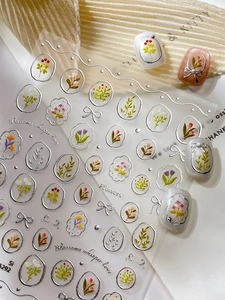 Detail of silver embossed floral nail stickers with tulips and bow accents on nails