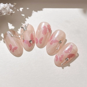 Faux ongles papillon élégants avec base rose gelée, strass brillants et breloques argentées