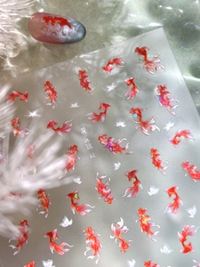 Detail of koi fish nail stickers with holographic shimmer and white flower patterns