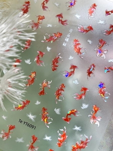 Close-up of holographic koi fish nail art stickers with white feathers background
